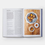 Open cookbook showing a page with text and an image of a dessert on a wooden board.