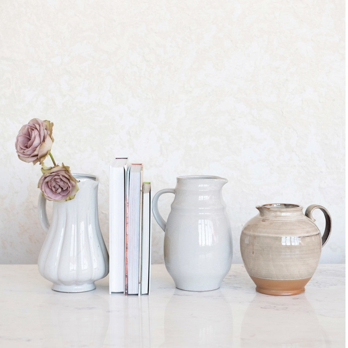 Set of ceramic vases and a pitcher on a white surface with a light gray background