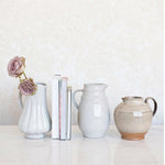 Set of ceramic vases and a pitcher on a white surface with a light gray background