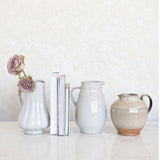 Set of ceramic vases and a pitcher on a white surface with a light gray background