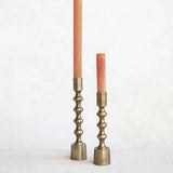 Tall and short Anderson taper holders in antique gold finish styled with blush taper candles on a linen surface.