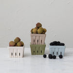 Three colorful berry baskets filled with lychees and blackberries on a light surface.