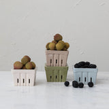 Three colorful berry baskets filled with lychees and blackberries on a light surface.