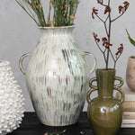 styled hand-painted stoneware vase with twin handles and a reactive glaze of cream, green, and brown styled with other vases