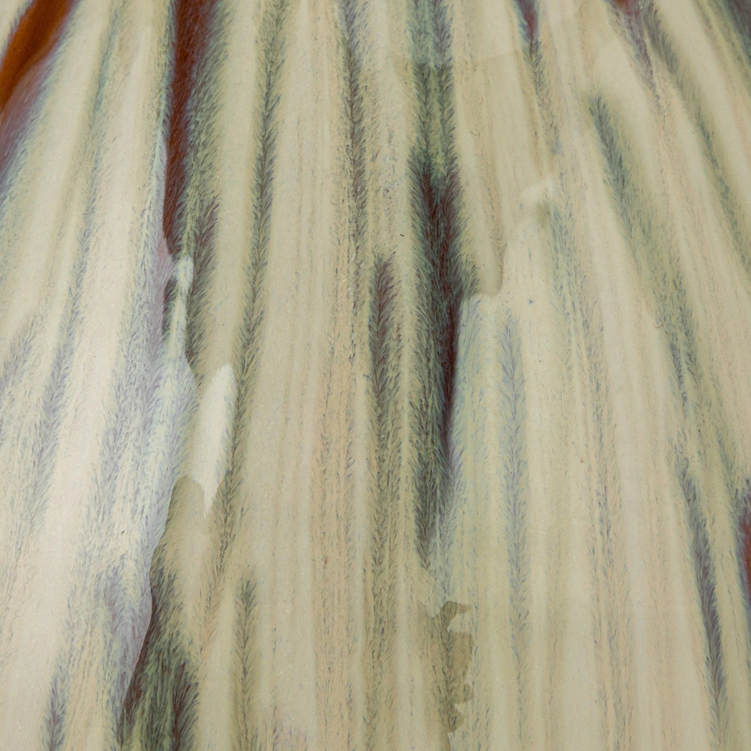 close up view of the reactive glaze of green, brown, and cream on the Miles Vase