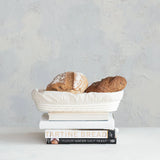Bread in a white bowl on top of books with a light gray background