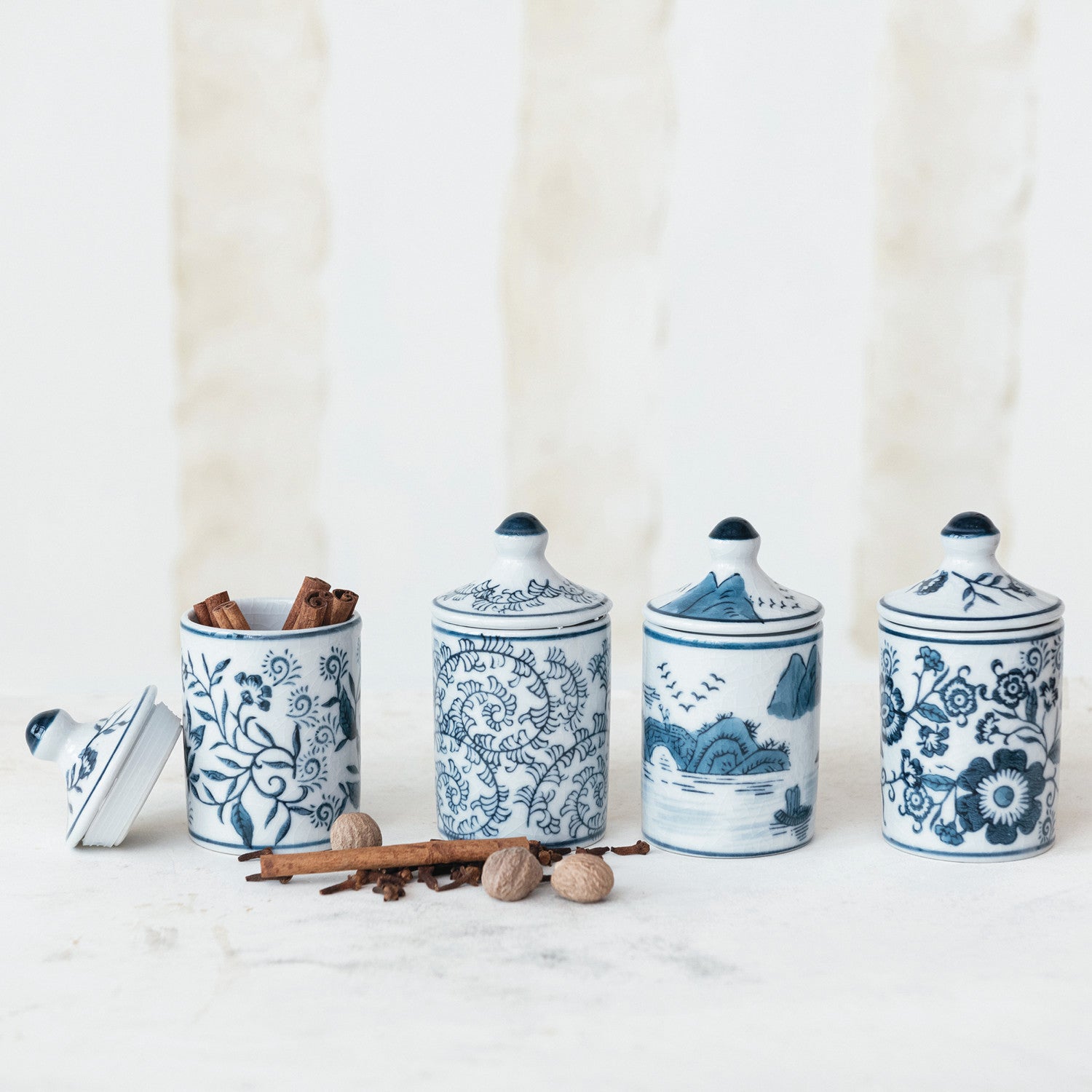 Set of four blue and white ceramic canisters with decorative patterns on a white background