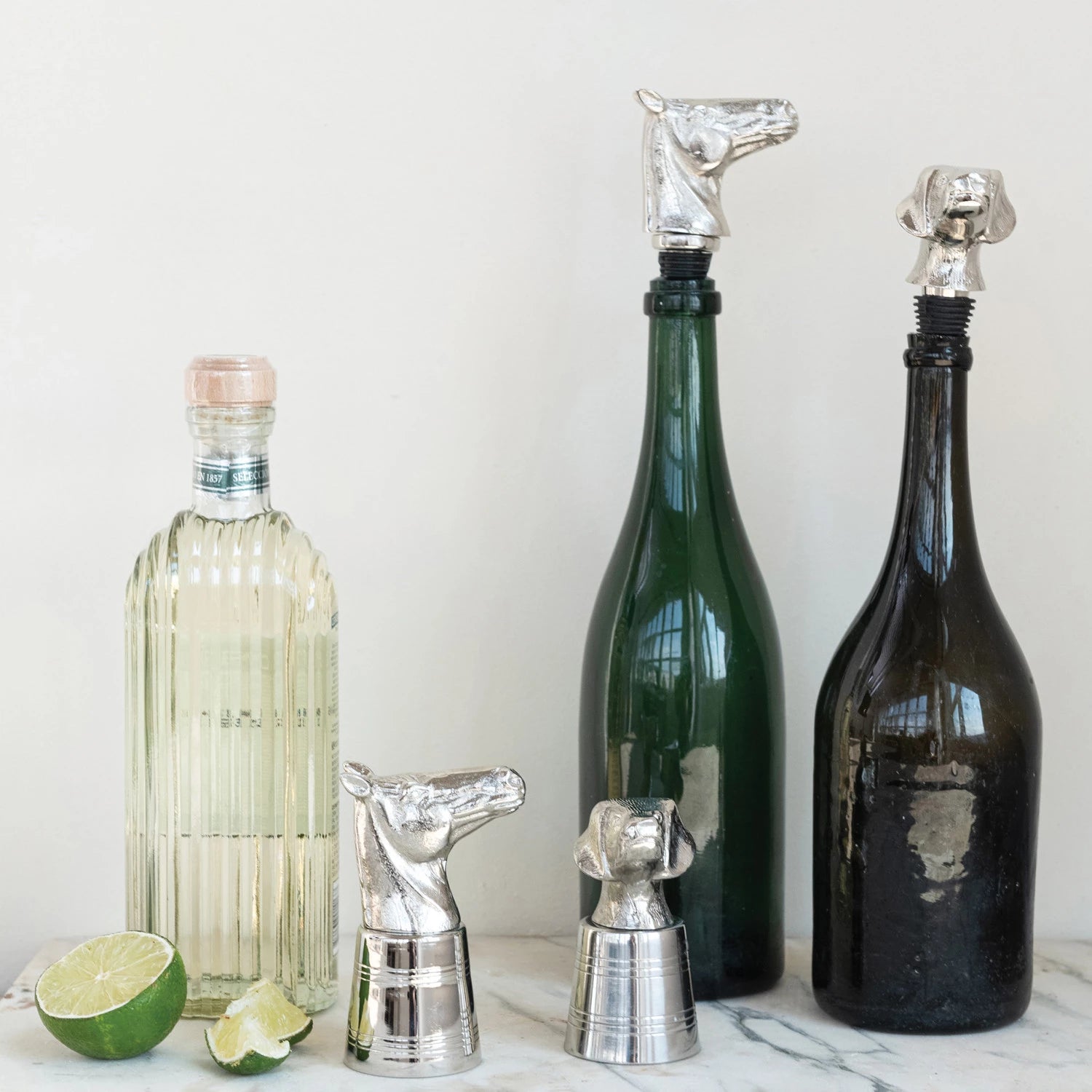 Three bottles with unique bottle stoppers shaped like animals on a light background.