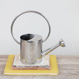 Silver watering can on a stack of books with a white background