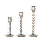 Three silver candle holders of different heights on a white background