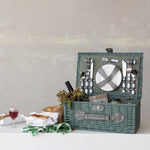 Picnic basket with cutlery and food on a white surface