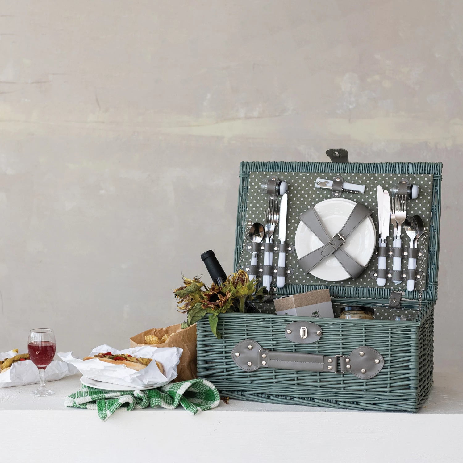 Picnic basket with cutlery and food on a white surface
