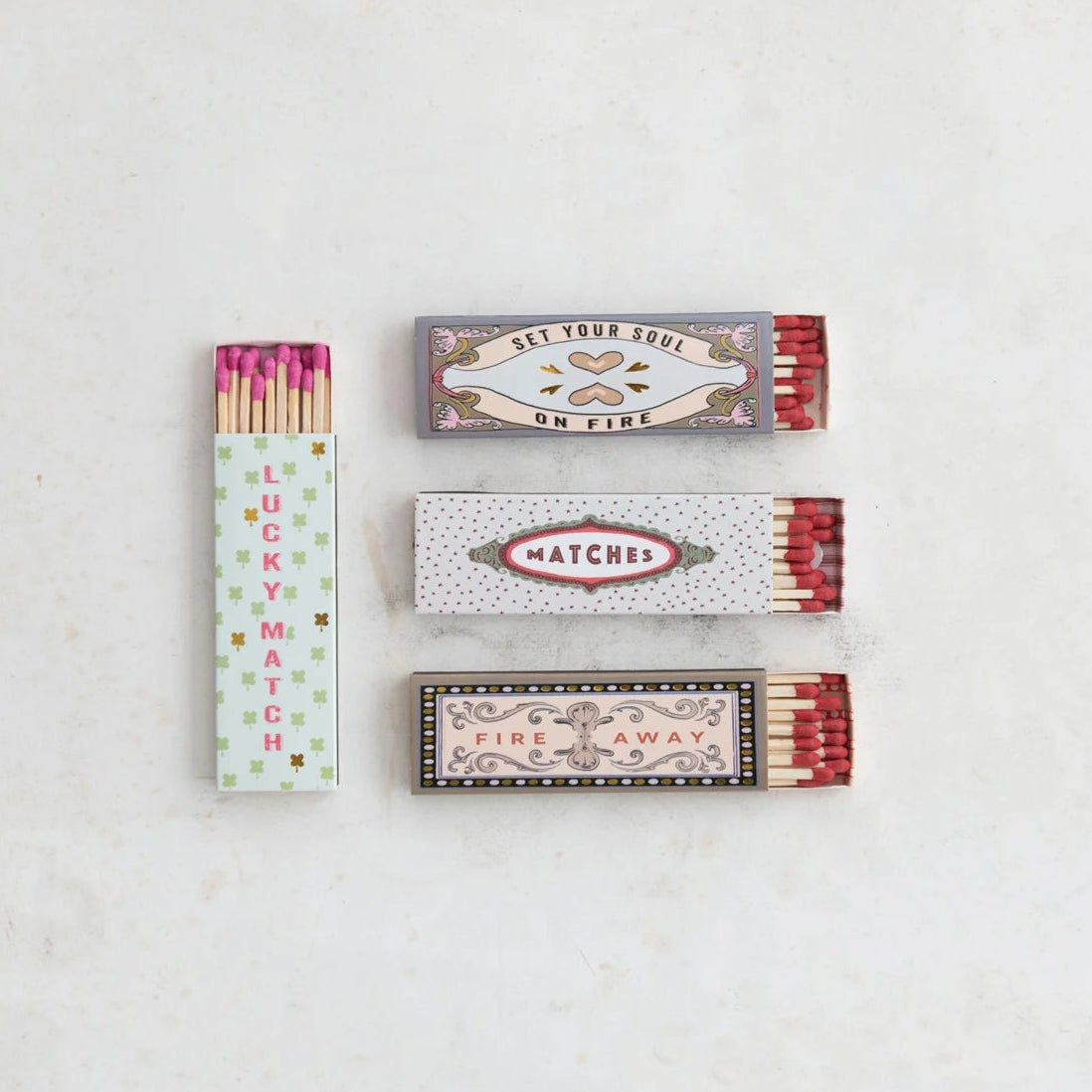 Four matchboxes with colorful labels on a light gray background