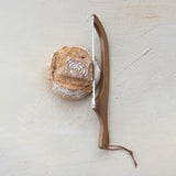 Wooden bread knife with a loaf of bread on a light gray surface