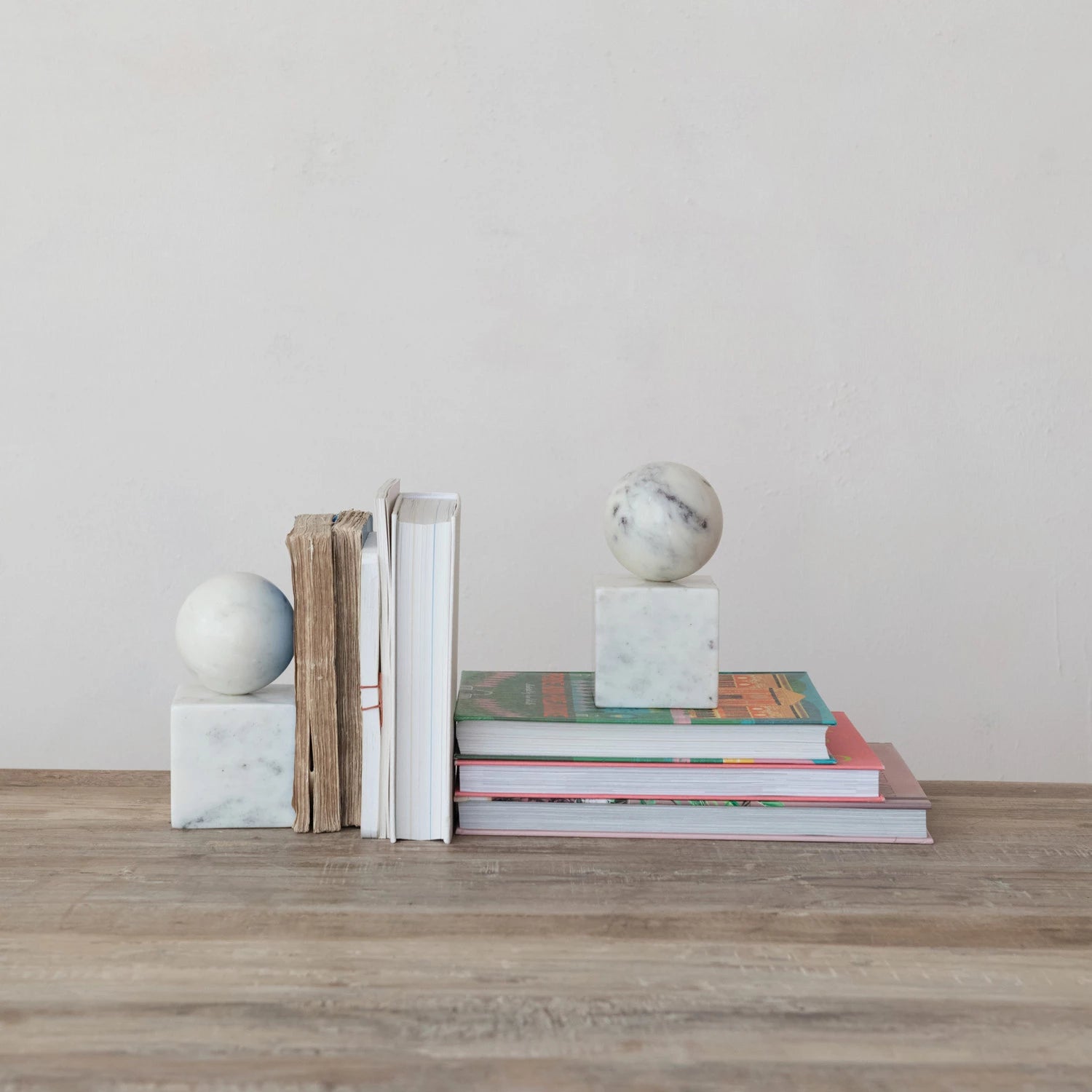 Stack of books with marble spheres on a wooden surface against a plain wall
