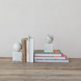 Stack of books with marble spheres on a wooden surface against a plain wall