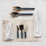 Set of salad servers with blue beaded handles on a light surface with packaging.