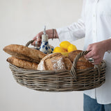 Person holding a woven basket with bread and lemons on a white surface