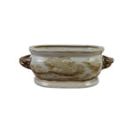 An oval ceramic planter pot with side handles, featuring a cream-colored glaze with brown landscape-style floral patterns and a matching base.