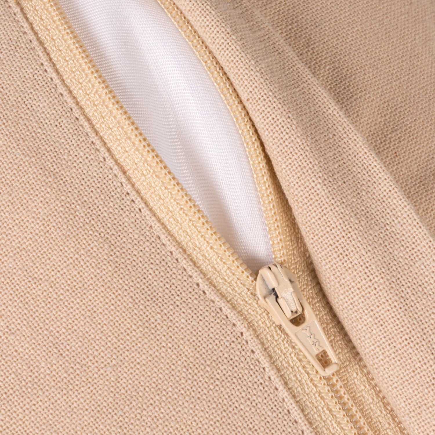Close-up of a beige knit fabric garment with a matching beige zipper and a white inner lining.
