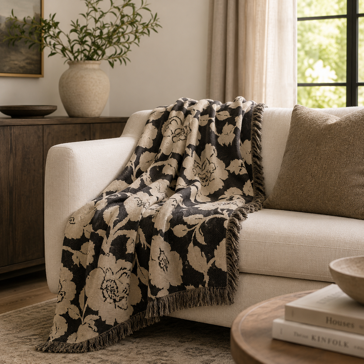 Floral patterned throw blanket draped over a white sofa in a living room setting.
