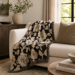 Floral patterned throw blanket draped over a white sofa in a living room setting.