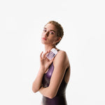 Woman wearing a dark purple swimsuit with a white background