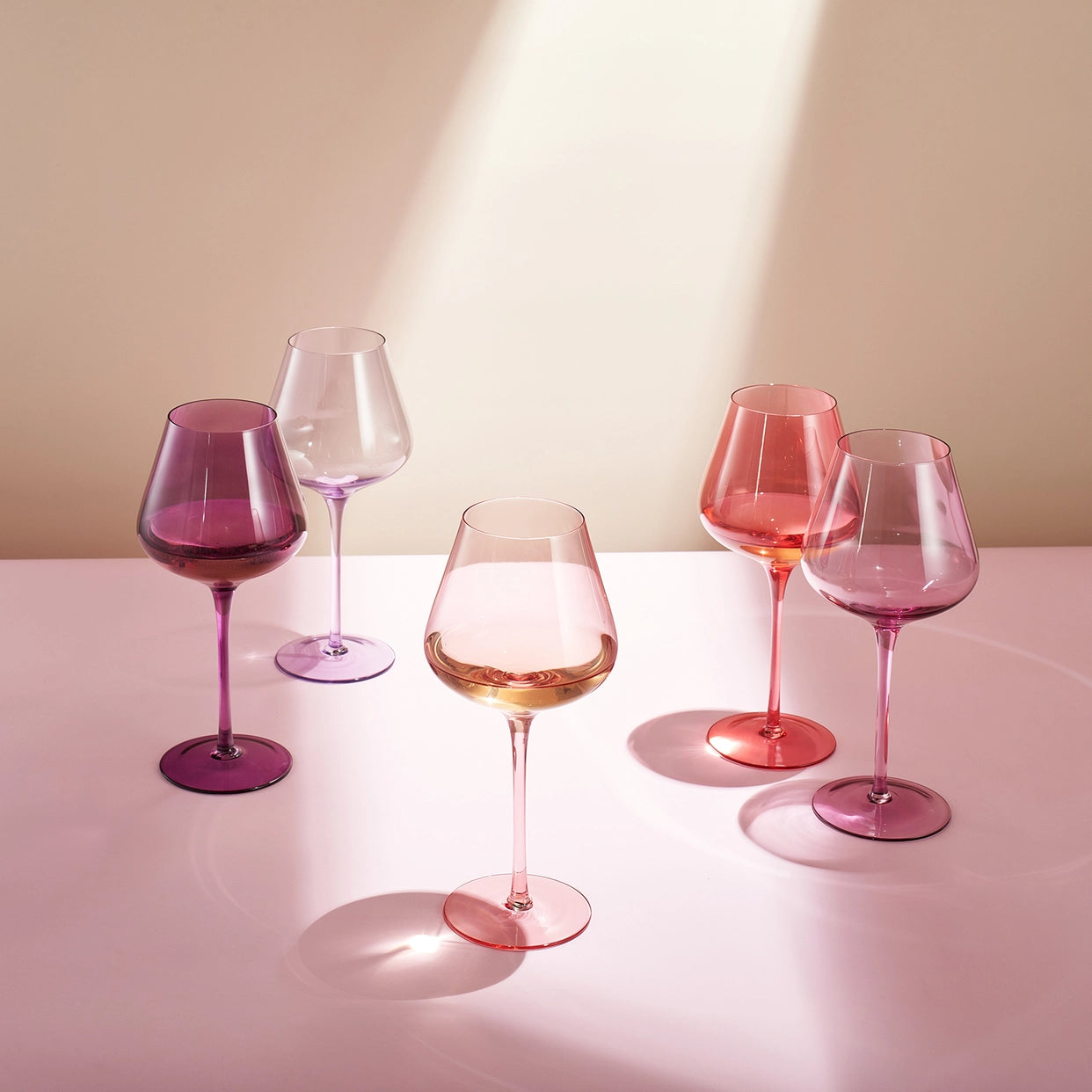 Set of colorful wine glasses on a light surface with a neutral background