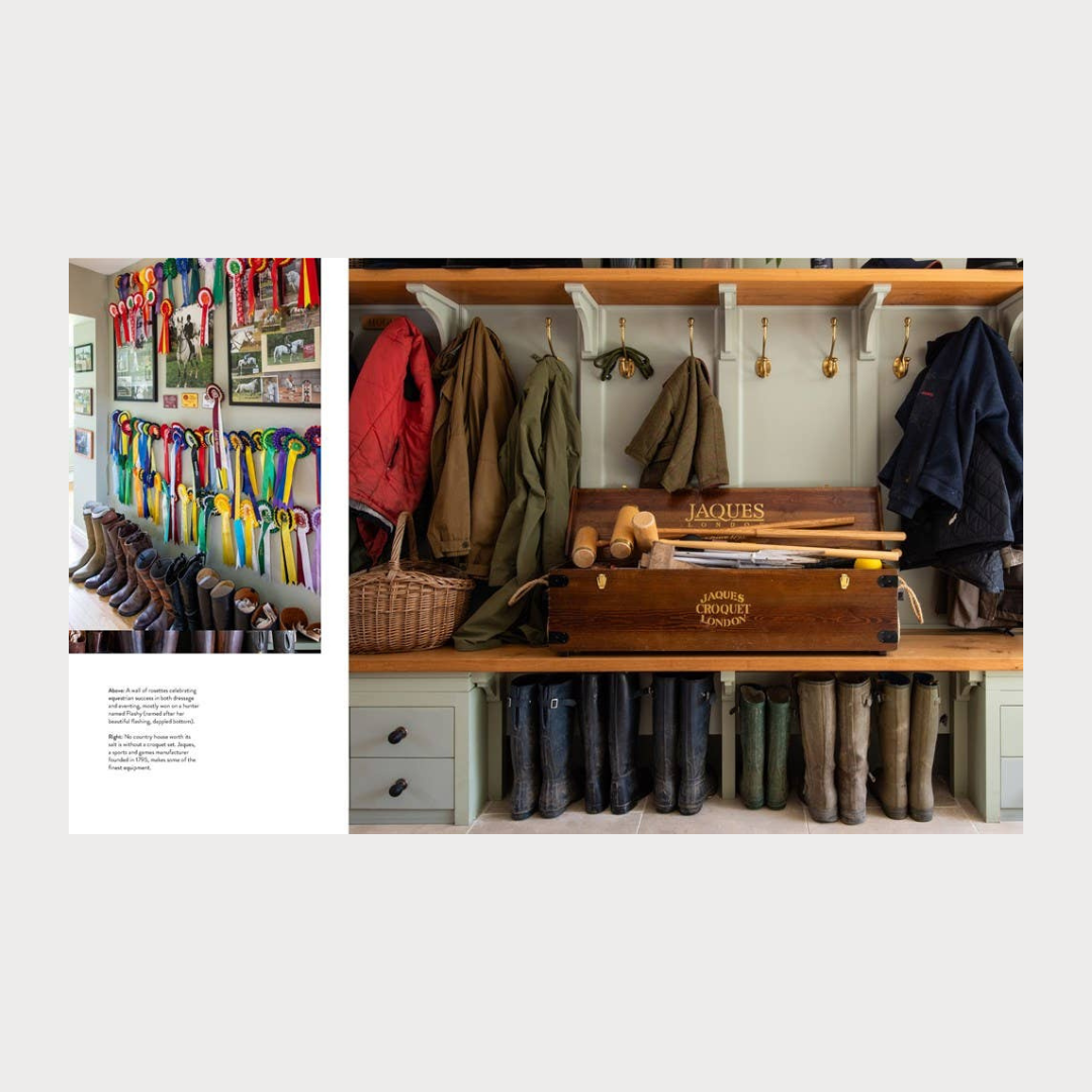 Coat rack with jackets, waders, and a wooden tool box in a room setting.