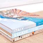 Stack of travel books with images of Italy on a beige surface