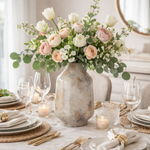 Decorative table setting with a vase of flowers on a white tablecloth.