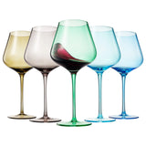 Five wine glasses of different colors with varying levels of red wine on a white background