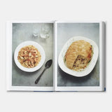 Open book showing two plates of food on a gray surface