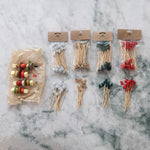 Assorted wooden skewers and toothpicks in packaging on a marble surface