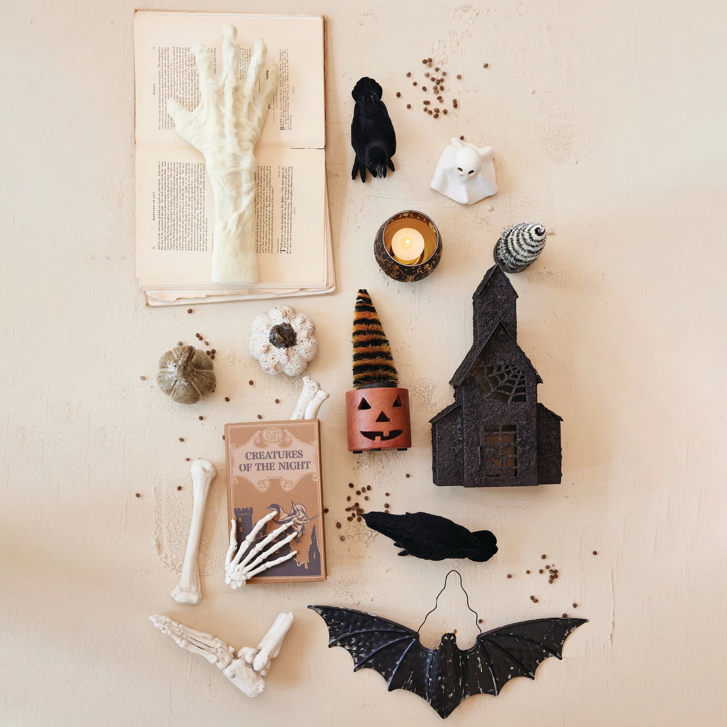 Halloween-themed decorations including a book, candles, and bats on a textured surface.