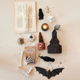 Halloween-themed decorations including a book, candles, and bats on a textured surface.