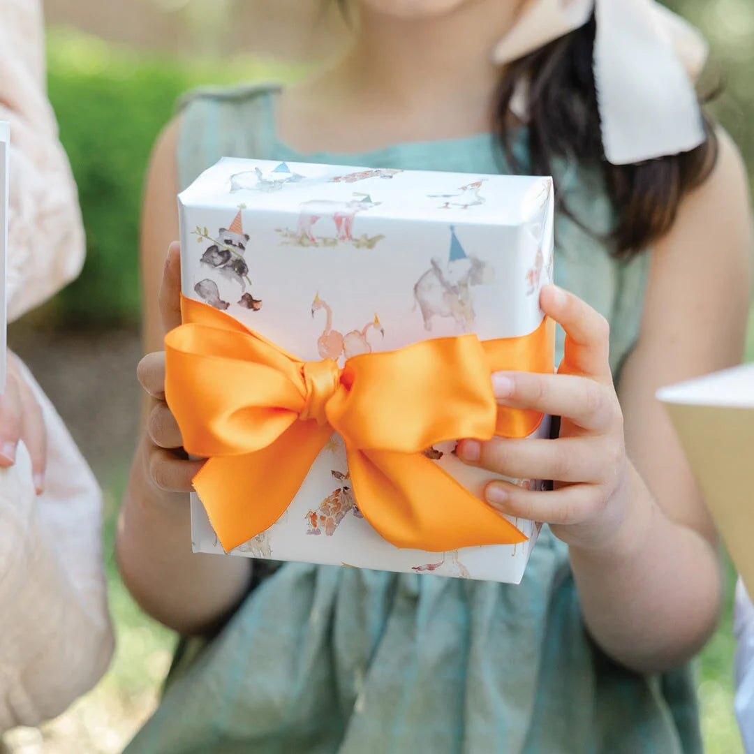 Child holding a gift box with an orange bow outdoors