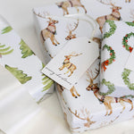 Christmas-themed gift wrap with reindeer and wreath designs on a white background.