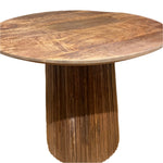 Round wooden dining table with a smooth top and a vertically grooved pedestal base.