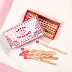 Matchbox labeled 'Spark Romance' with matches on a light pink background