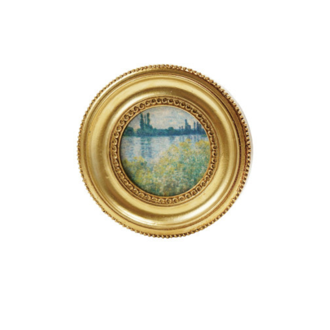 Decorative circular art magnet with a gold frame on a white background