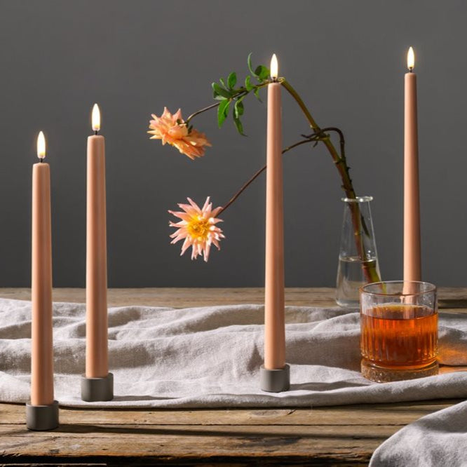 Candle holder with pink candles on a wooden table with a dark background