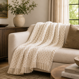 Beige patterned throw blanket draped over a beige sofa in a living room setting.