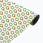 Roll of wrapping paper with green wreath and red bow pattern on a white background