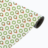Roll of wrapping paper with green wreath and red bow pattern on a white background