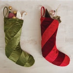 Green and red striped Christmas stockings with decorative elements on a light wooden surface.