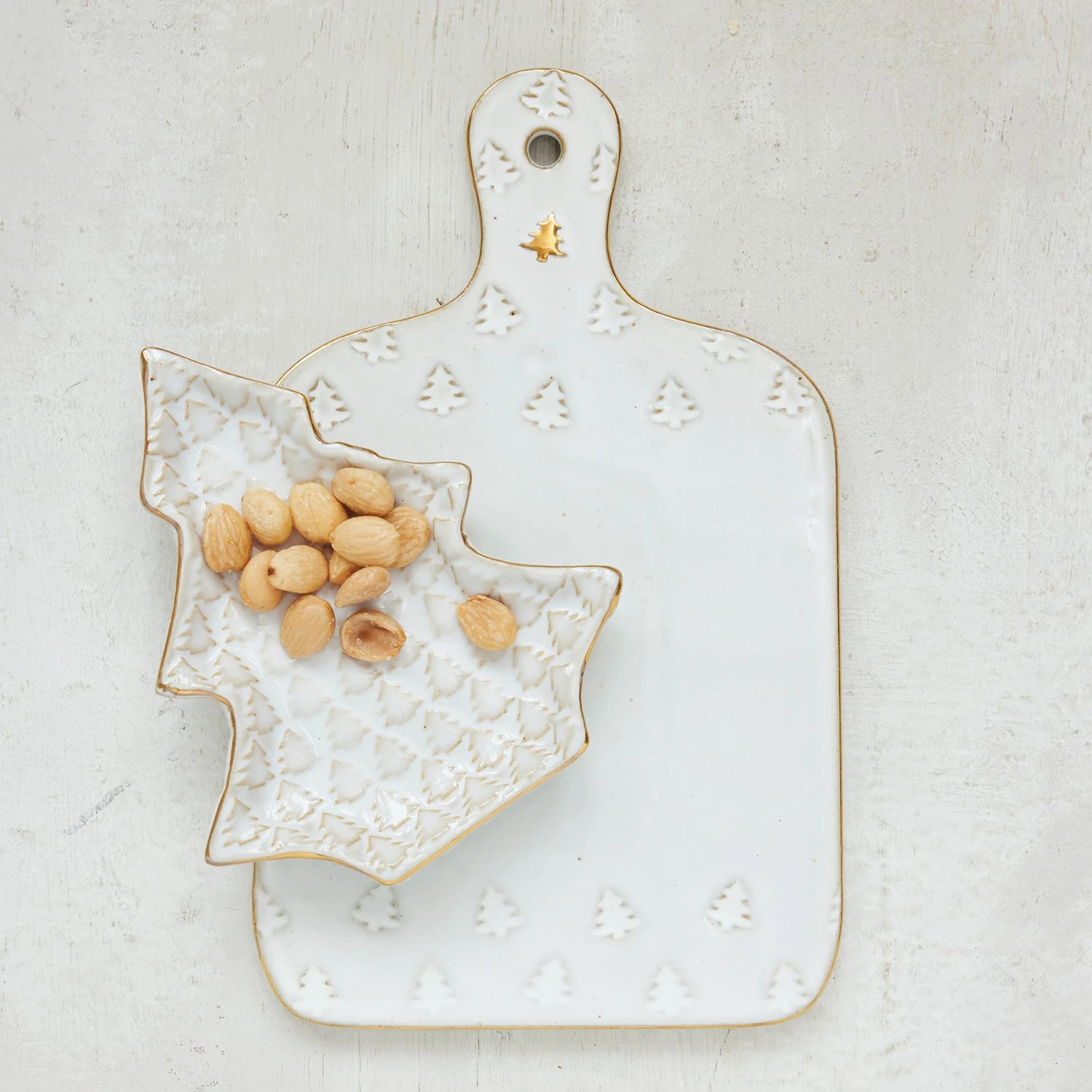 Decorative ceramic cutting board with a small bowl of nuts on a light background