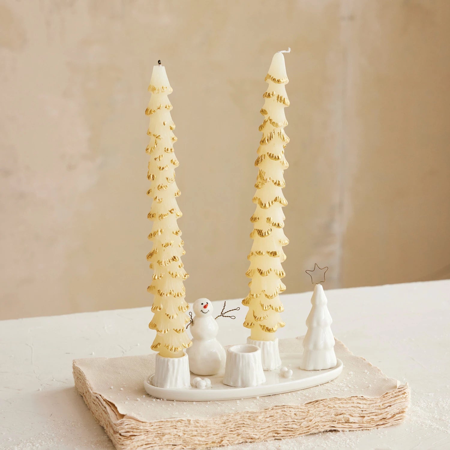 Decorative candles shaped like Christmas trees on a white surface with a neutral background