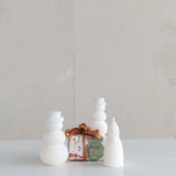 Three white textured figurines with a small gift box labeled 'Peace' on a light background