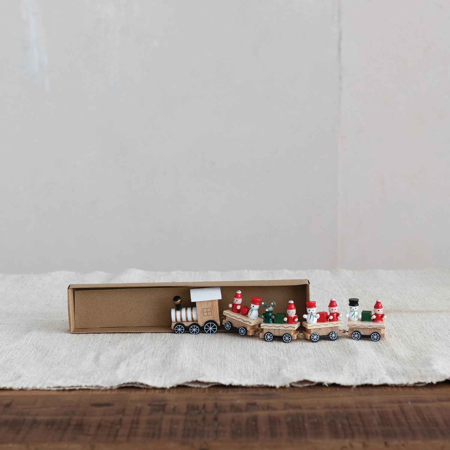 Wooden toy train set with Santa Claus figures on a white surface